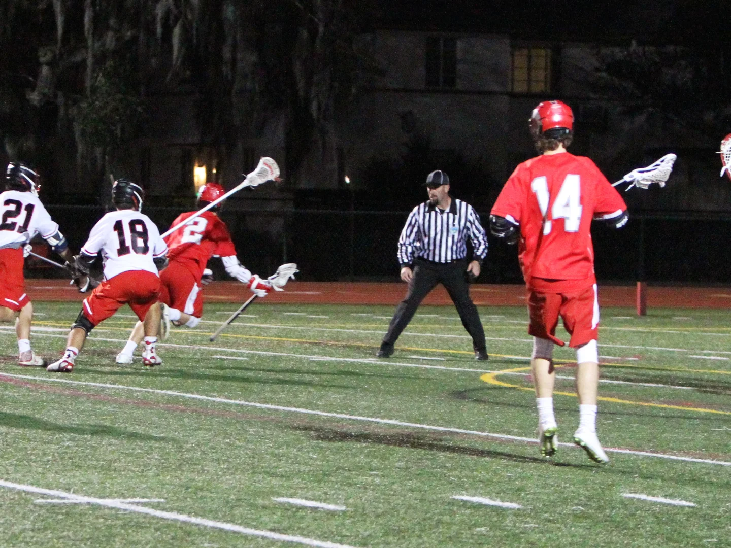 A lacrosse official watches play near the goal during a night game
